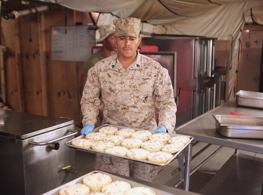 A food service specialist preparing miniature pizzas at the Harvest Falcon dining facility.