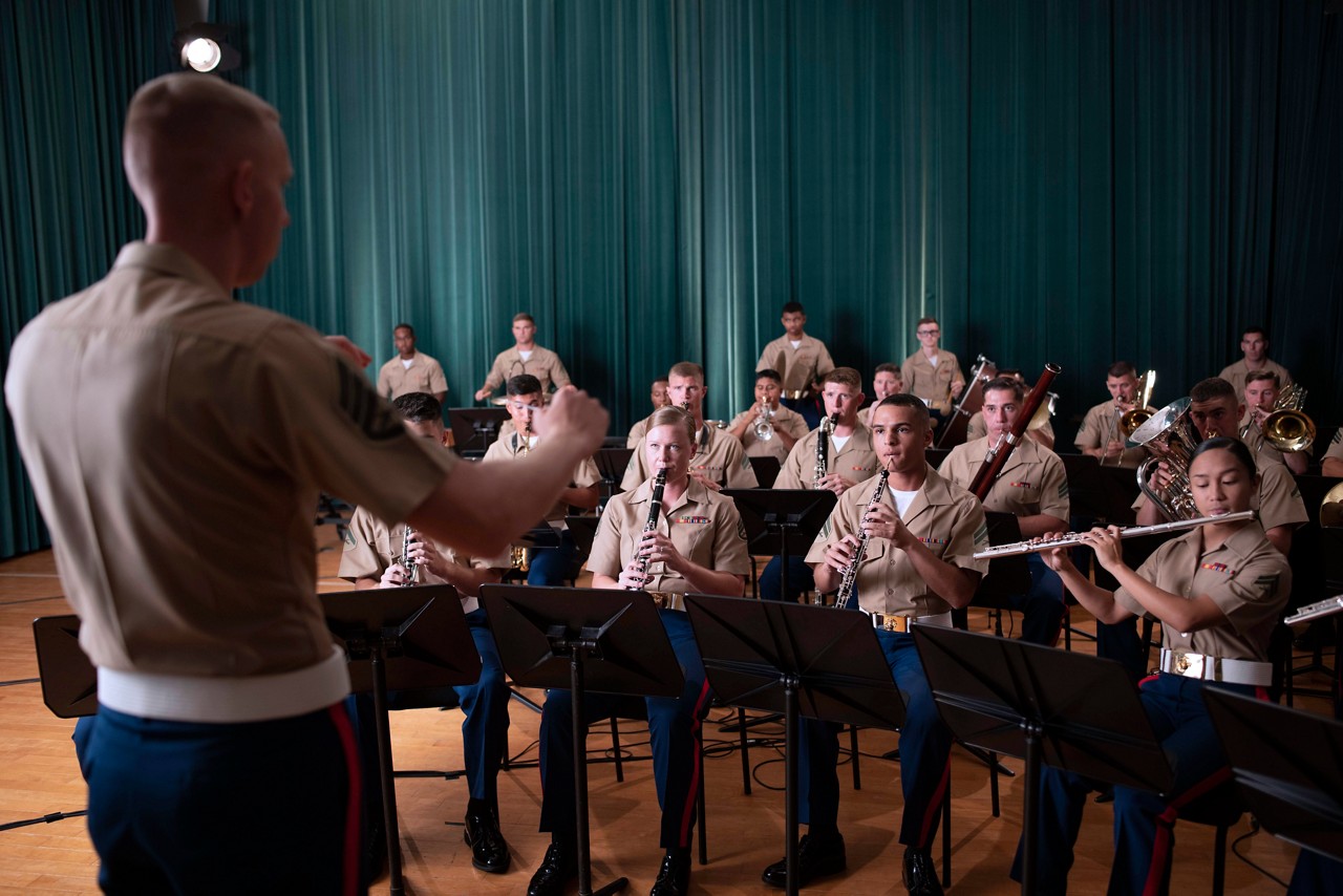 Marine in the music MOS field directing a band during a ceremony.