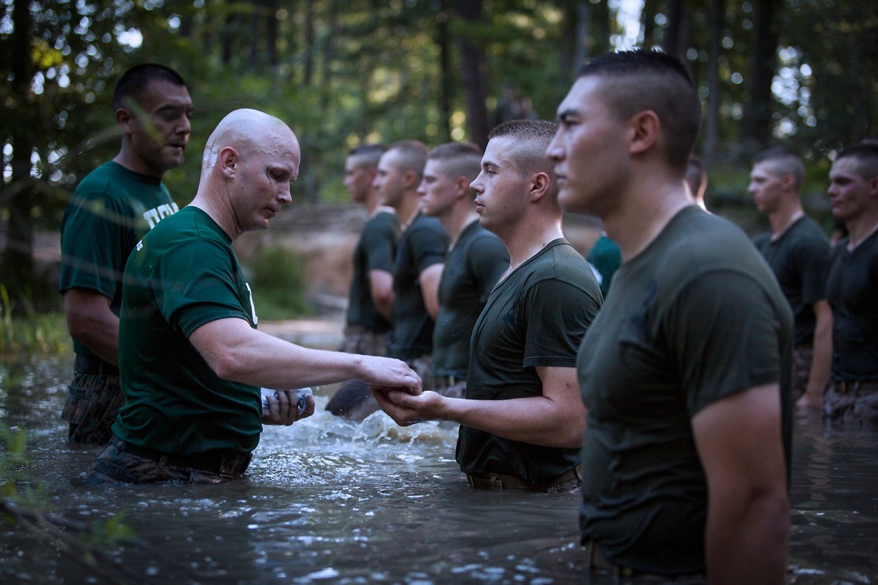 Captain Raymond Fernandez, the commanding officer of Lima Company, and Gunnery Sgt. Brandon Harvell, a sergeant instructor, present the Eagle, Globe and Anchor emblem to candidates in the waters of Big Ford during the Medal of Honor run course at Marine Corps Officer Candidates School aboard Marine Corps Base Quantico, Virginia, July 2, 2019. The Medal of Honor run is the final physical fitness event the candidates run before earning their Eagle, Globe and Anchor emblem, signifying that they have earned the title of United States Marine. The mission of Officer Candidates School is to educate and train officer candidates in Marine Corps knowledge and skills within a controlled and challenging environment in order to evaluate and screen individuals for the leadership, moral, mental, and physical qualities required for commissioning as a Marine Corps officer. (U.S. Marine Corps photo by Lance Cpl. Phuchung Nguyen)