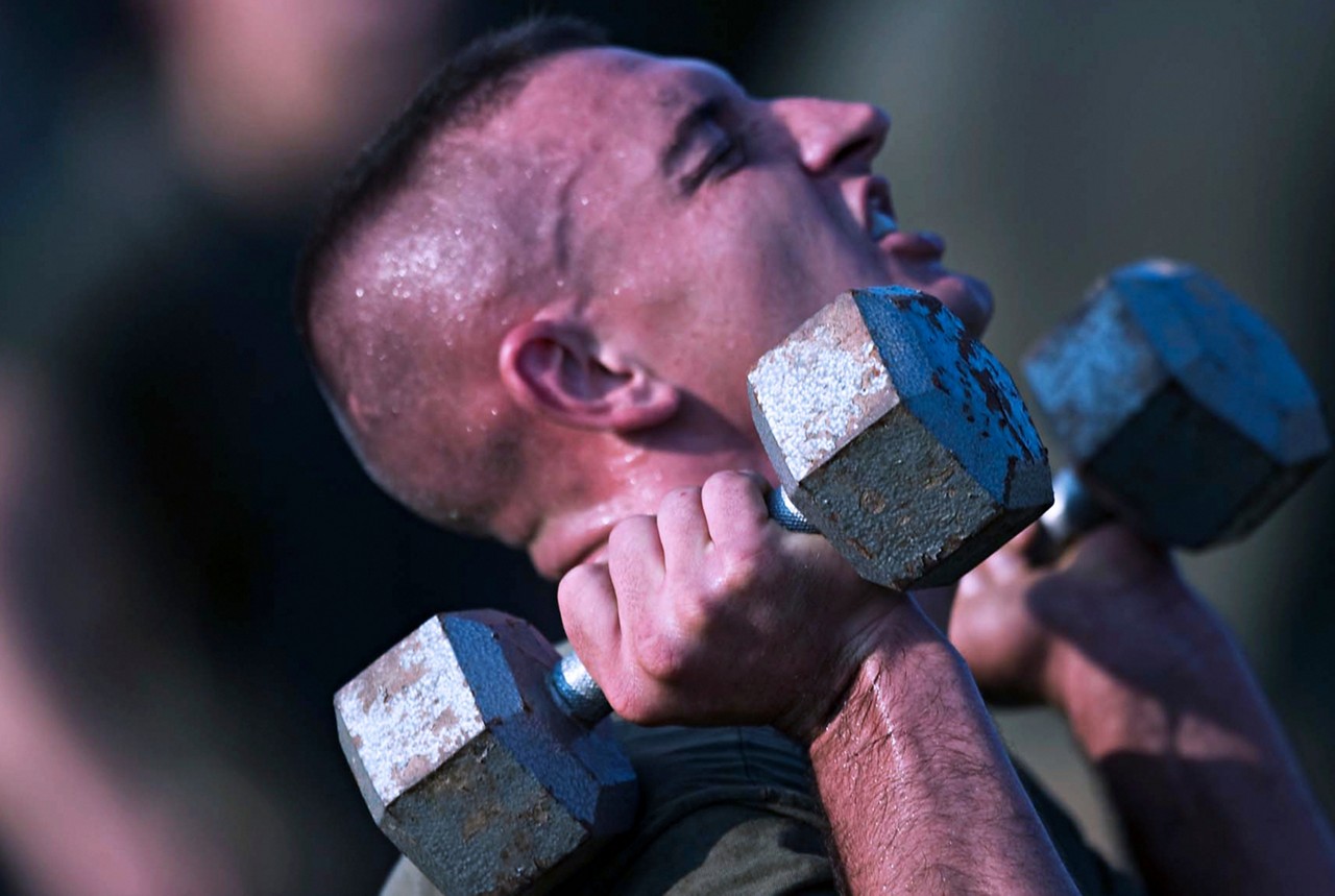 Aspiring Marine lifting dumbbells during fitness test.
