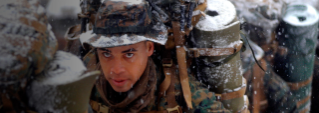 A Marine Officer marches as snow falls.