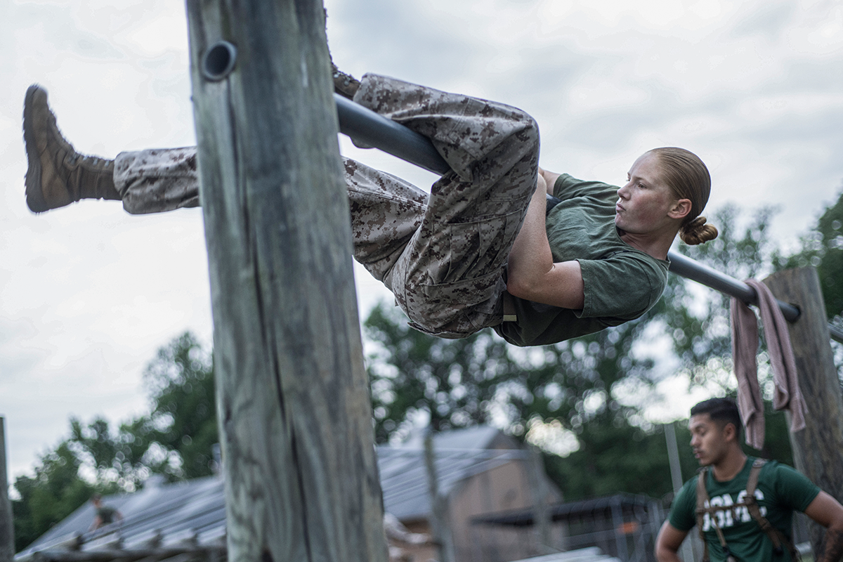 Marine officer candidate climbs vertical obstacle during physical fitness training on obstacle course at Officer Candidates School.