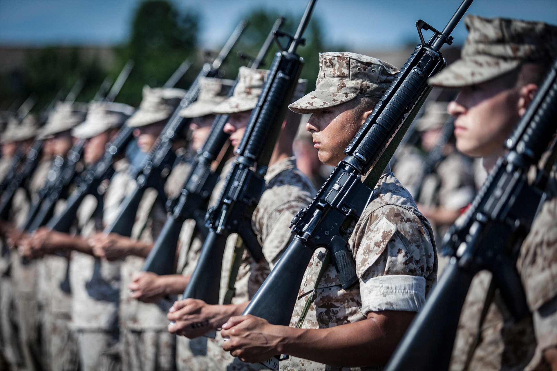 Marine officers in desert camouflage uniforms holding rifles during Basic School graduation ceremony formation.