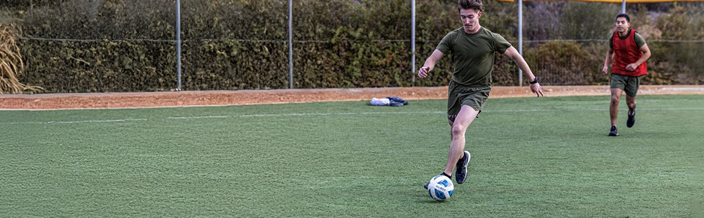 Marines playing soccer together on base field, demonstrating camaraderie and recreational activities.