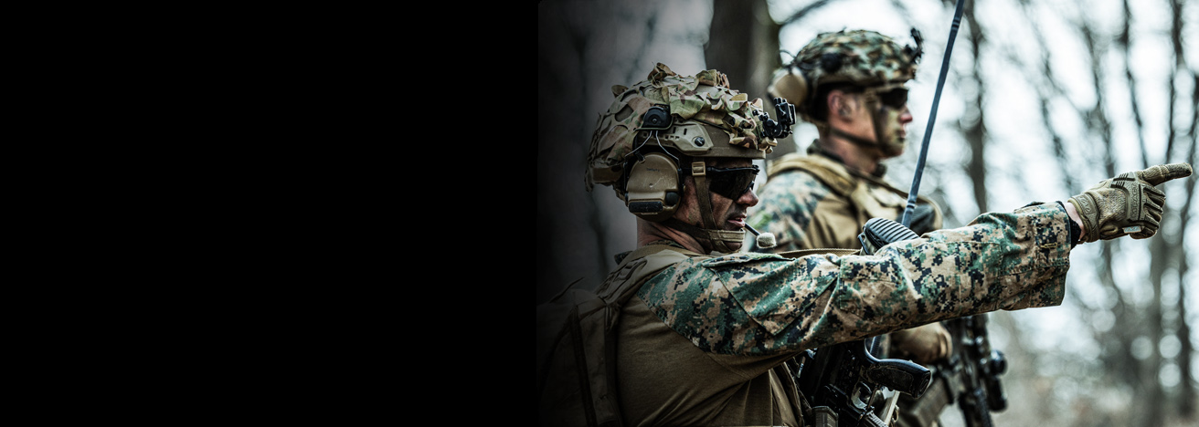 Marines in combat helmets and digital camouflage conducting tactical training exercise in wooded area.
