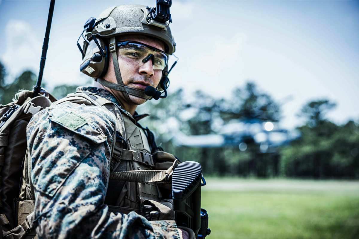 Marine in tactical helmet with communication equipment and digital camouflage uniform during training.