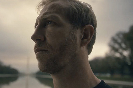 Jake Harriman, the founder of the NGO Nuru International, stands in front of a reflecting pool and the Washington Monument.
