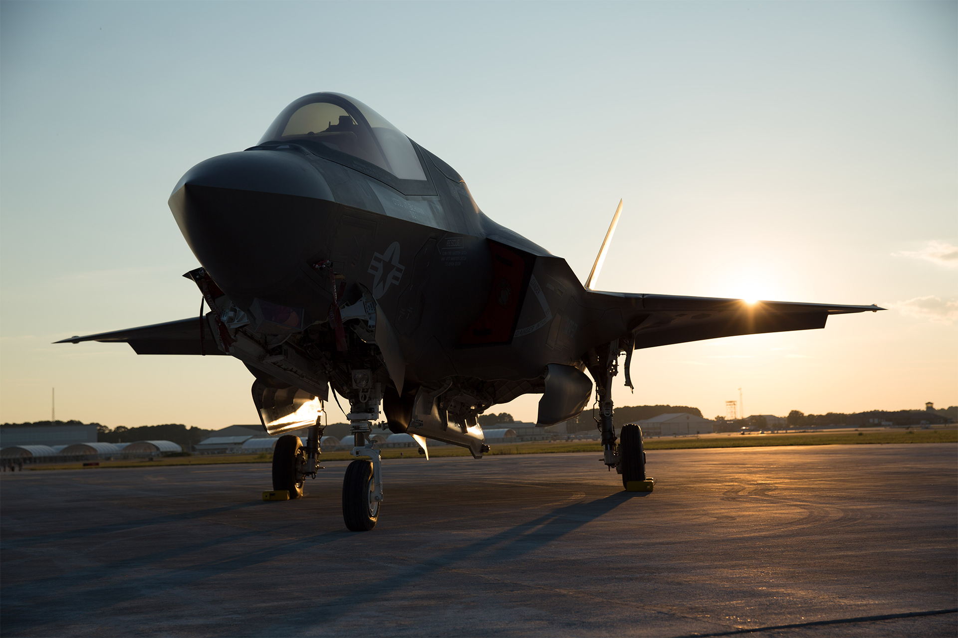 F-35B Lightning II stealth fighter jet on flight line at sunset with open weapons bay doors.