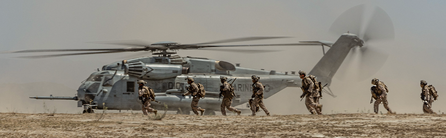 Marines disembark from CH-53 Sea Stallion helicopter during air-ground task force training operation in desert terrain.