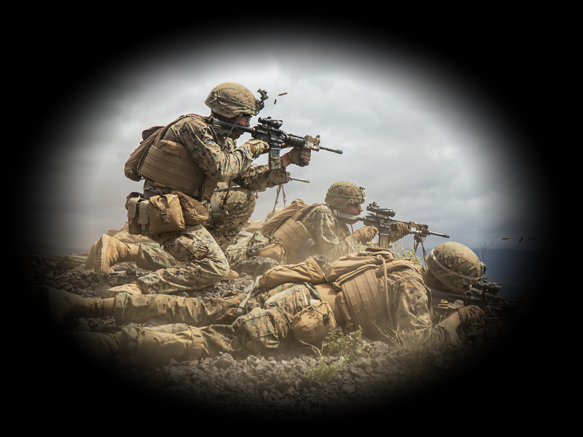 Marine fire team in desert combat positions with rifles conducting tactical operations in arid terrain.
