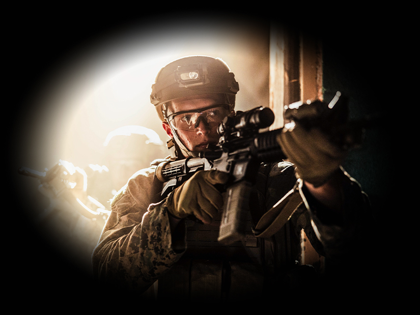 Marine rifleman aiming scoped rifle during urban combat training exercise at Camp Lejeune.