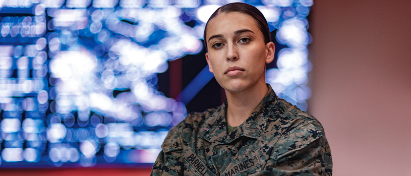 First Lieutenant Annie Parnell in camouflage uniform standing before digital display screen.
