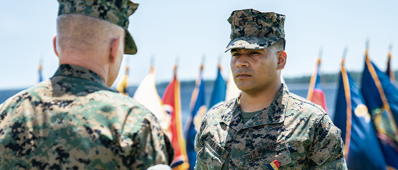 Lance Corporal Kevin Grajeda in camouflage uniform standing at attention during military ceremony.