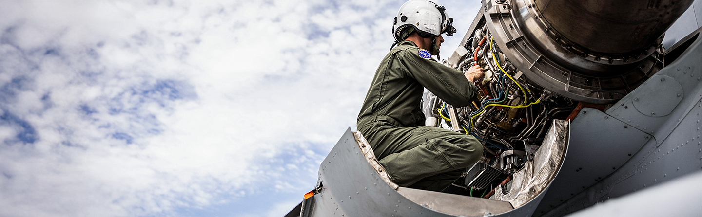 A CH-53K aircraft maintenance Marine conducts maintenance on the engine of a CH-53K helicopter.