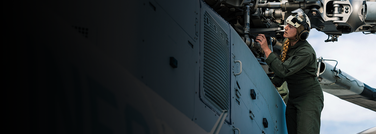 Captain Kricket Harper performs pre-flight inspection on helicopter engine compartment at Camp Lejeune.