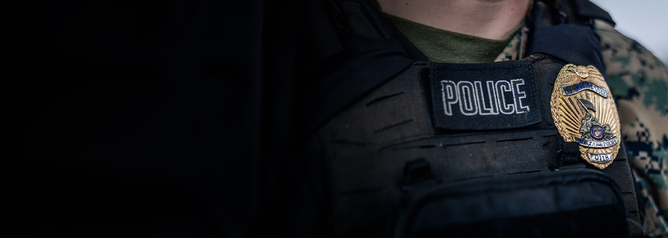 A Marine wears a protective vest that has a "Police" patch on it as well as a bright gold, metallic military police badge.