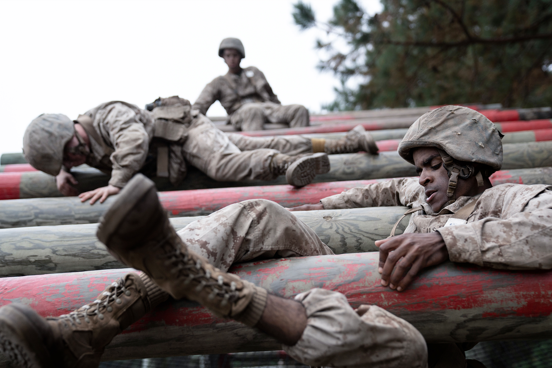 Marine recruits in training gear navigate crucible obstacle course, showing physical challenge and teamwork.
